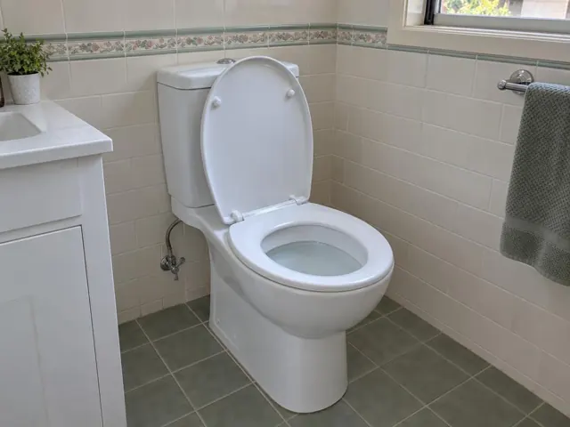Clean white toilet in a tiled bathroom with dry floor and towel rail in Coogee